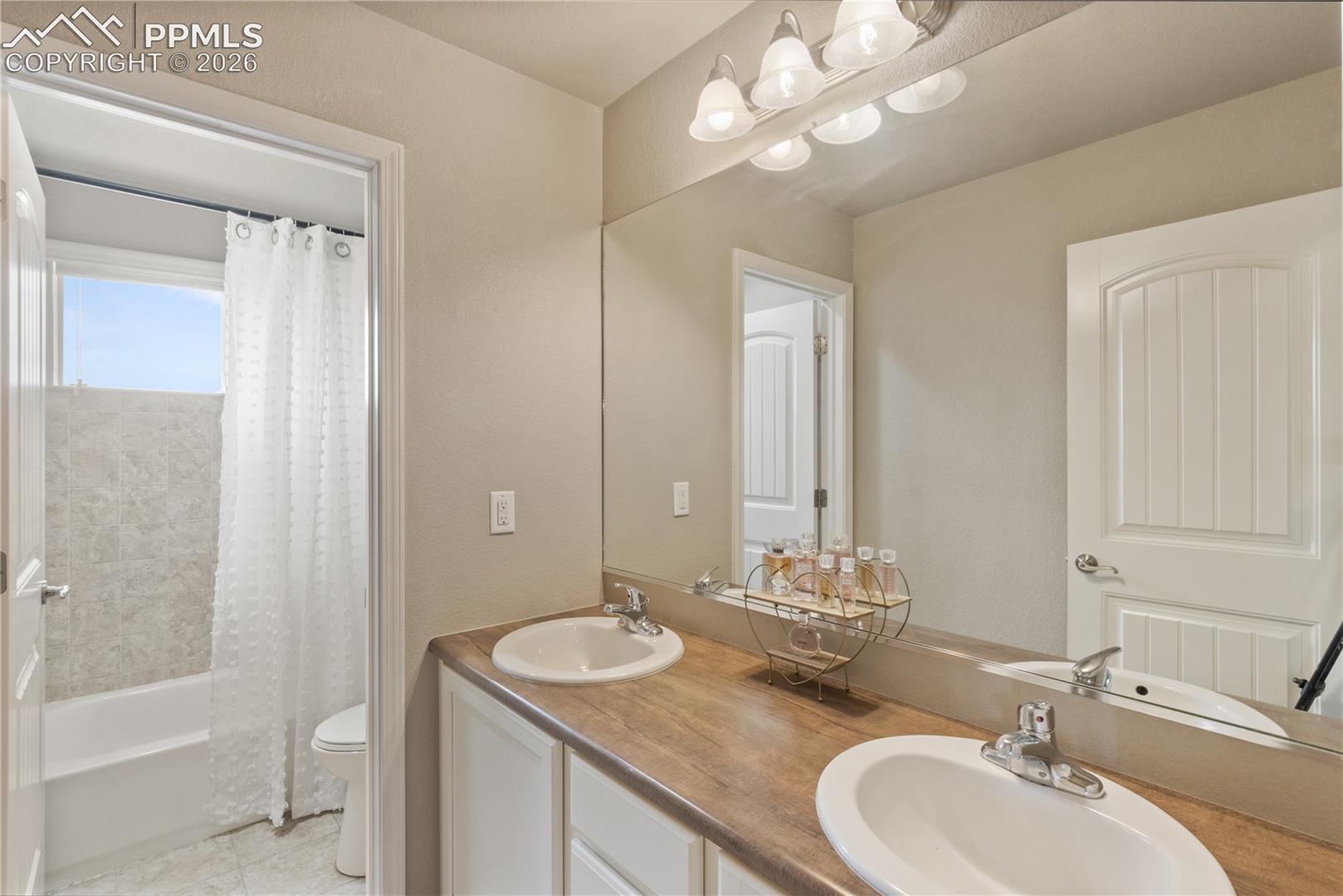 Bathroom with double vanity and shower / bath combination with curtain