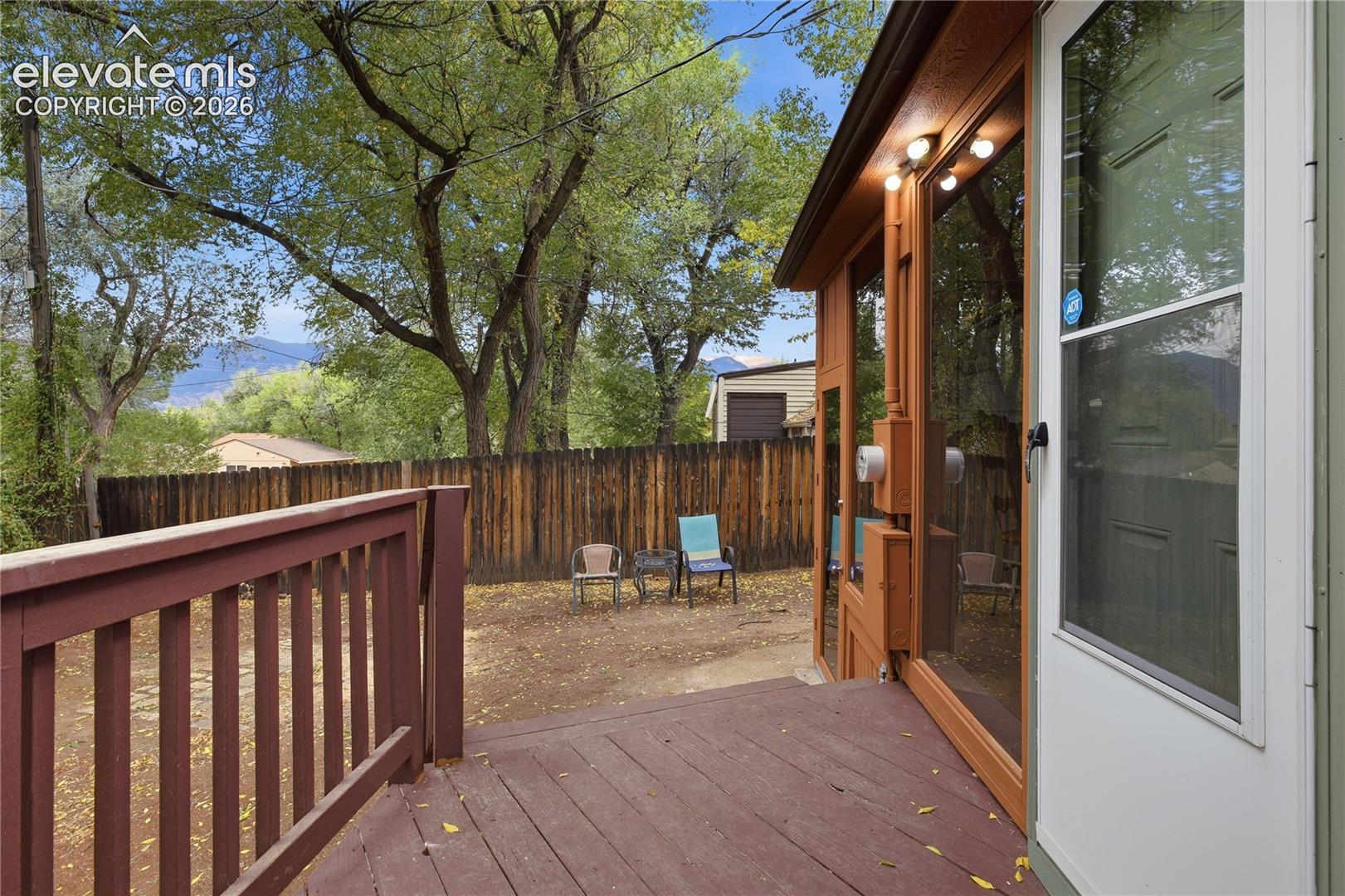Elevated wood deck featuring a railing, natural-finish vertical wood fencing, and a mountain backdrop
