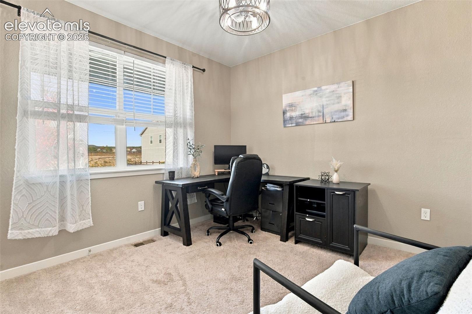 Room featuring neutral wall tones, plush wall-to-wall carpeting, large window with horizontal blinds, and a drum-style ceiling light fixture