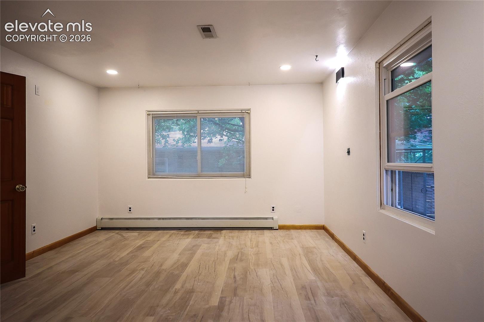 Main bedroom Recessed ceiling lighting, wood-finish flooring, baseboard heating, and two windows providing natural illumination
