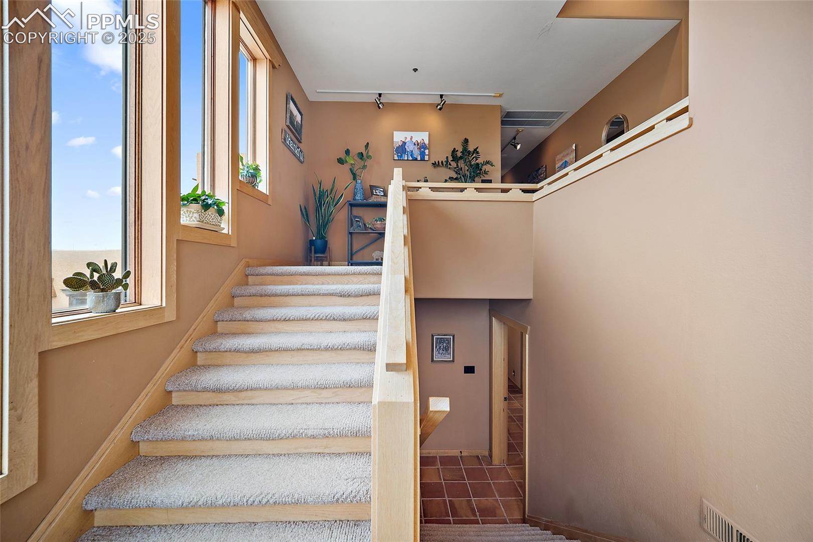 Stairs with tile patterned floors and track lighting