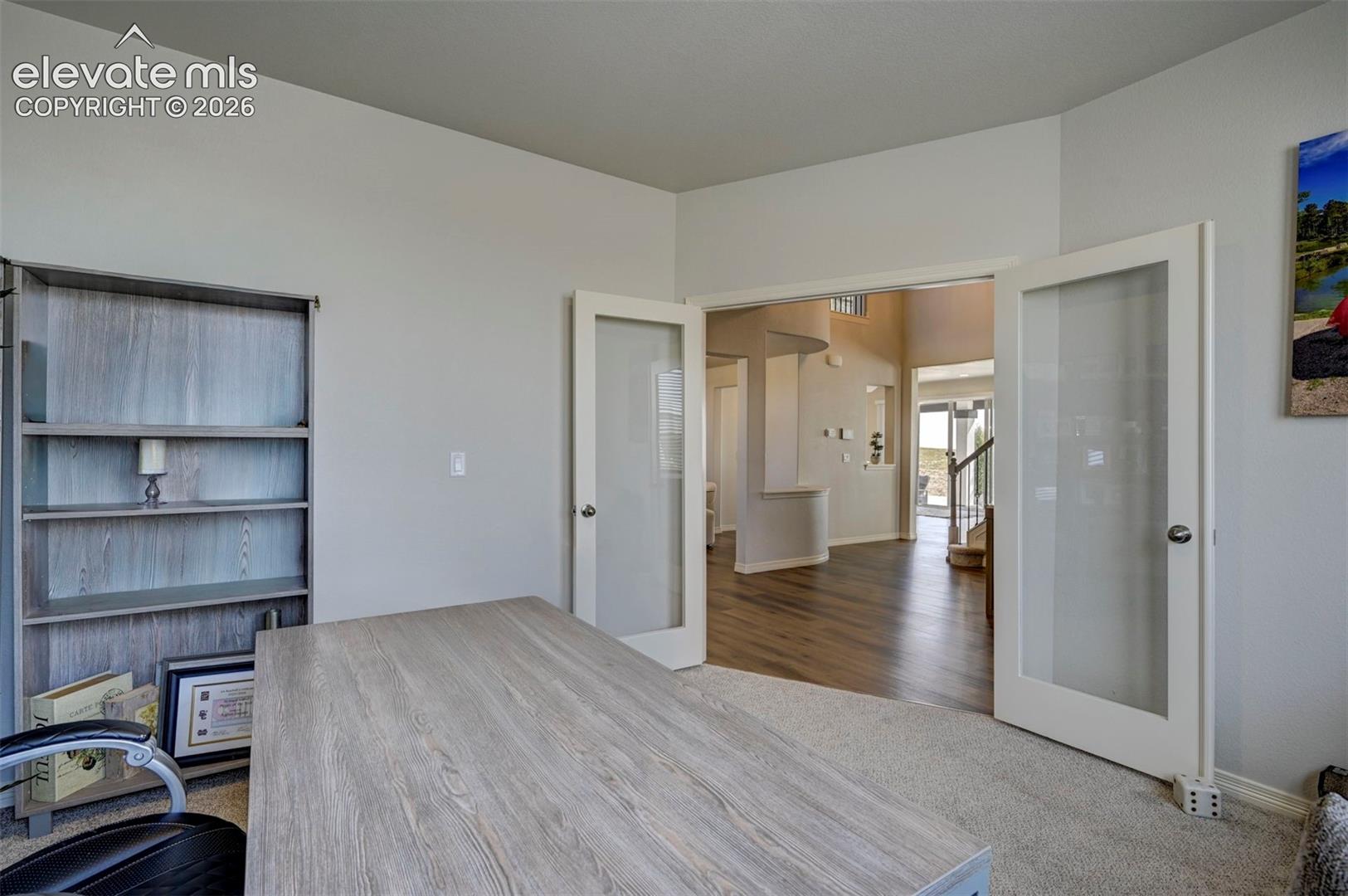 Double French doorsnpanels open to a spacious entry hall featuring wood-finish flooring and a staircase with wood treads and white risers