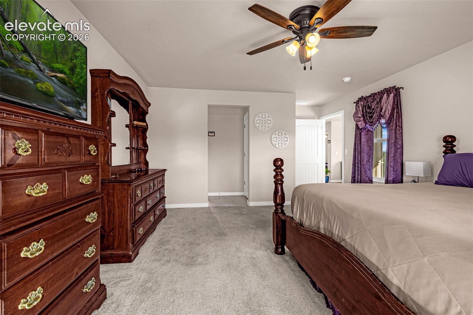 Ceiling fan with integrated multi-light fixture, neutral carpeting, and multi-panel interior doors