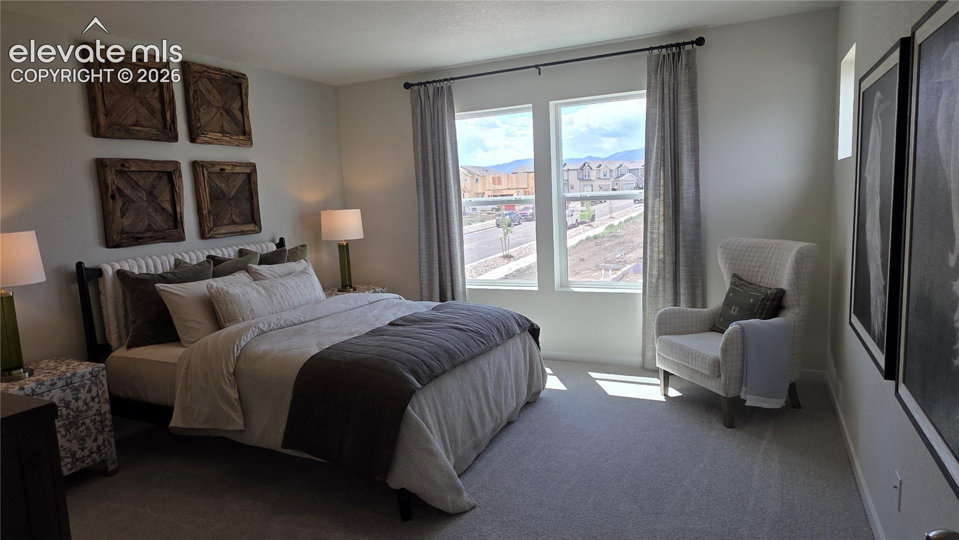 bedroom with decorative wooden wall panels, two tall windows with curtains, and an armchair by the wall