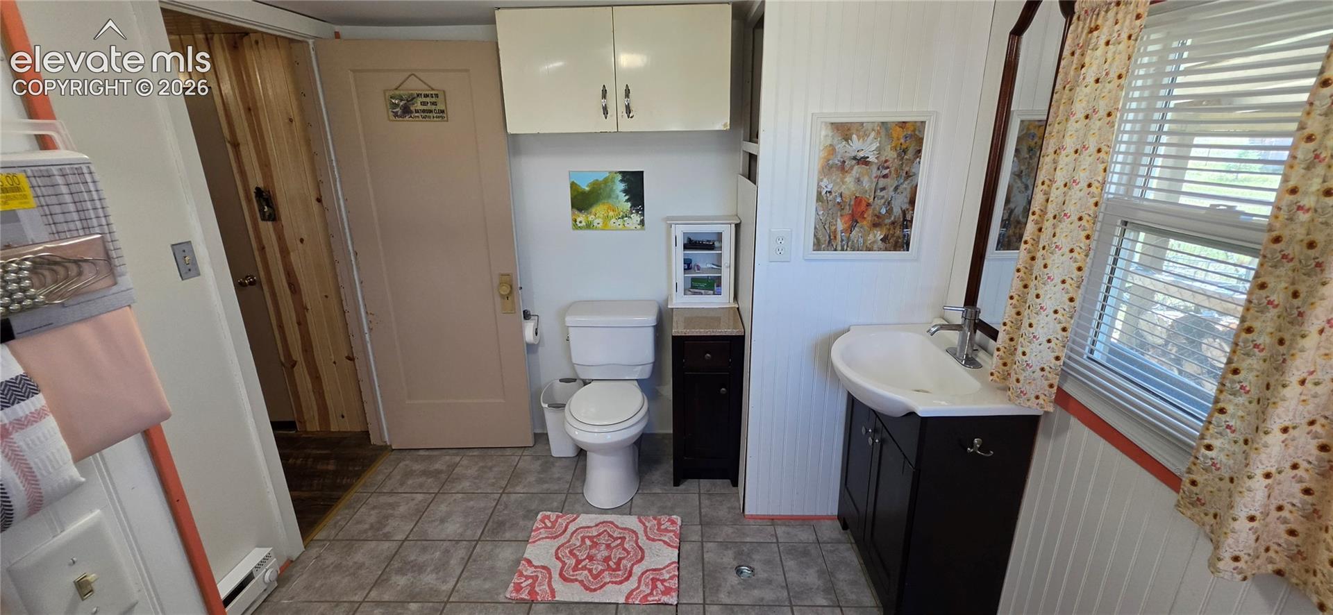Bathroom featuring tile flooring, a white vanity with an integrated sink, and an overhead built-in cabinet