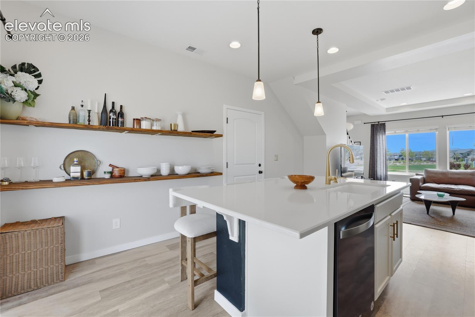 Kitchen island featuring a white countertop, undermount sink, and brass-finish faucet