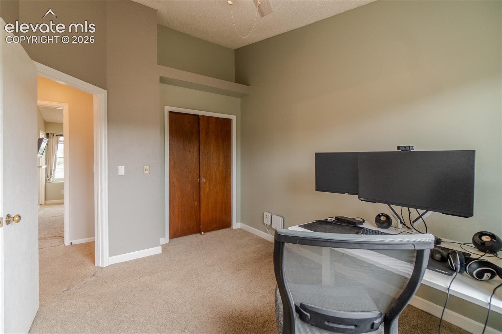 Carpeted room with bi-fold wood doors and overhead architectural detail