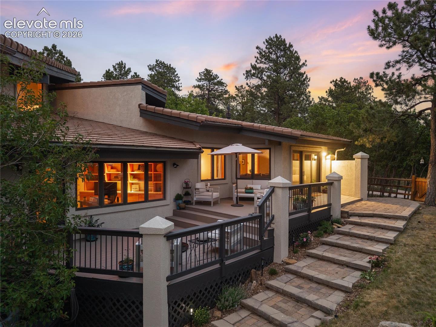 Multi-level rear exterior featuring a composite deck, stucco siding, and a tile roof