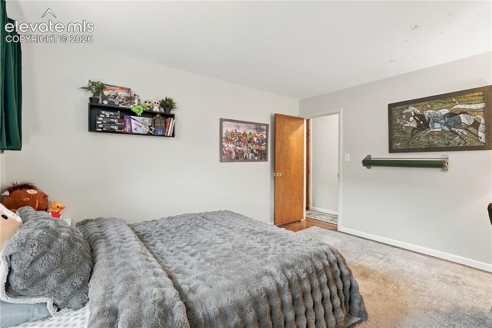 Neutral-toned walls, wall-mounted shelving unit, and wood-finish door