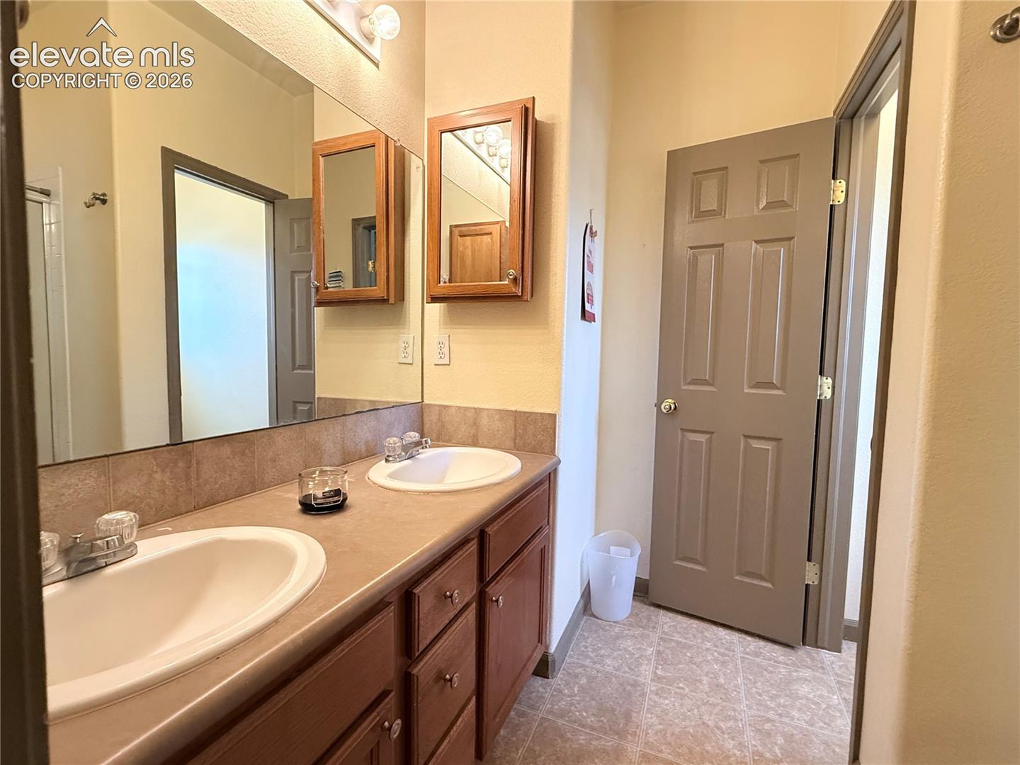 Double vanity with individual sinks, wood-finish cabinetry, and laminate countertops