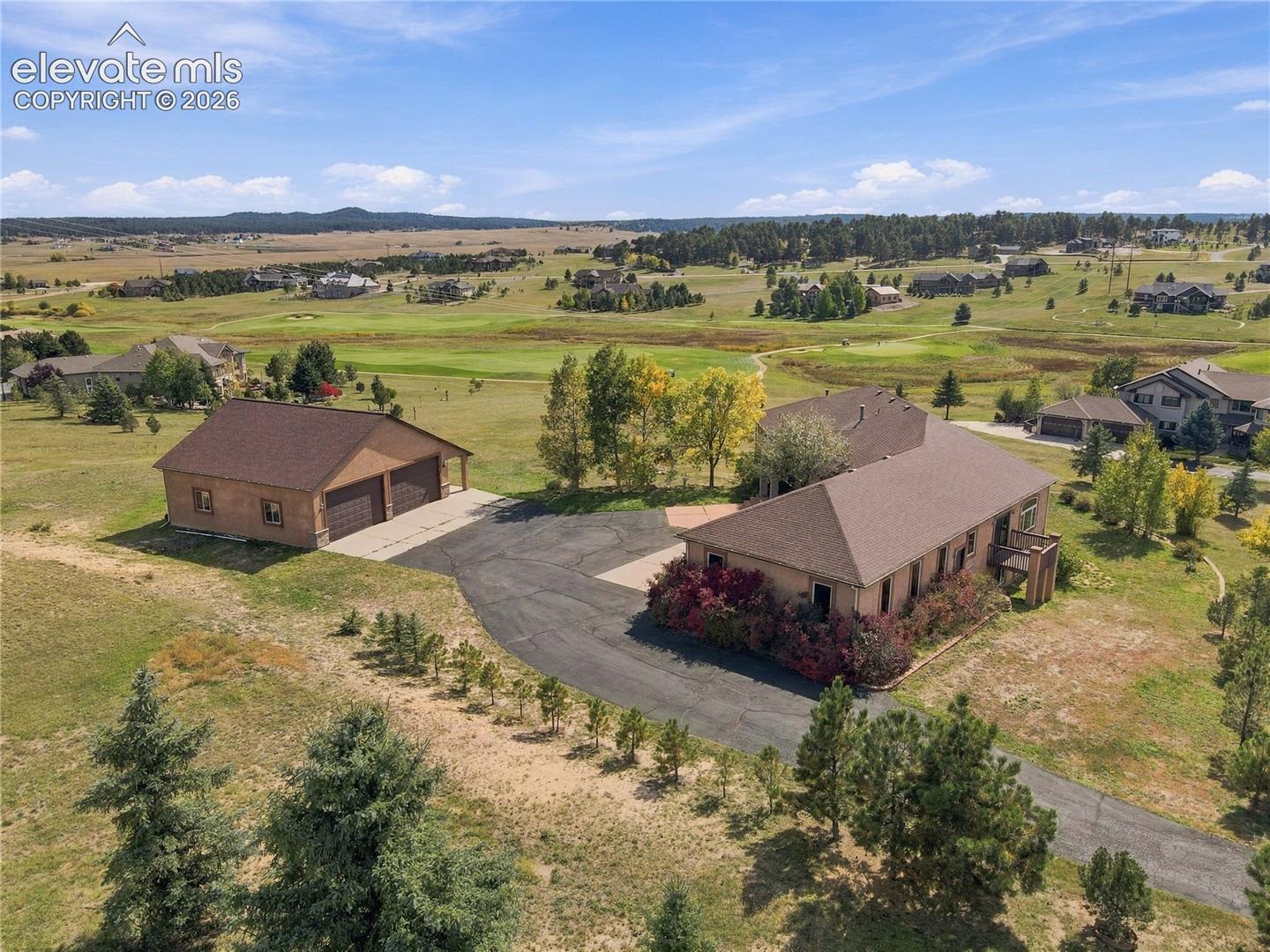 Expansive property featuring a main residence, a detached garage structure, a paved driveway, and established landscaping