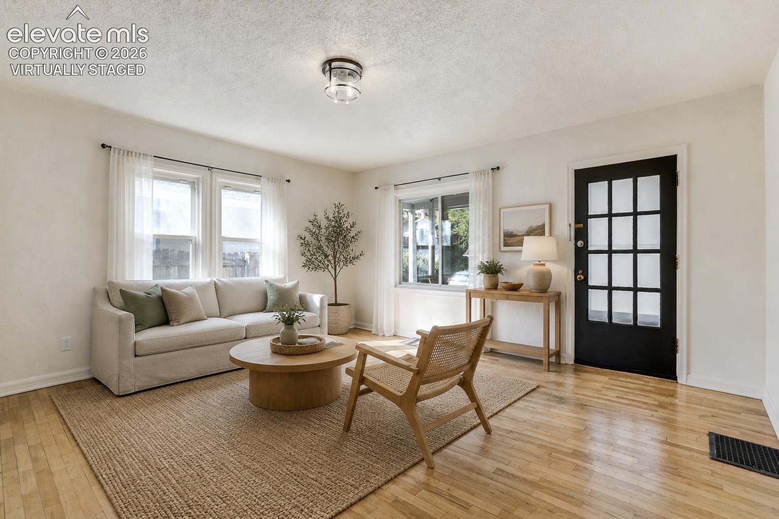 Virtually Staged.  Light-filled interior featuring wood-finish flooring, multi-pane glass entry door, and crisp neutral wall tones