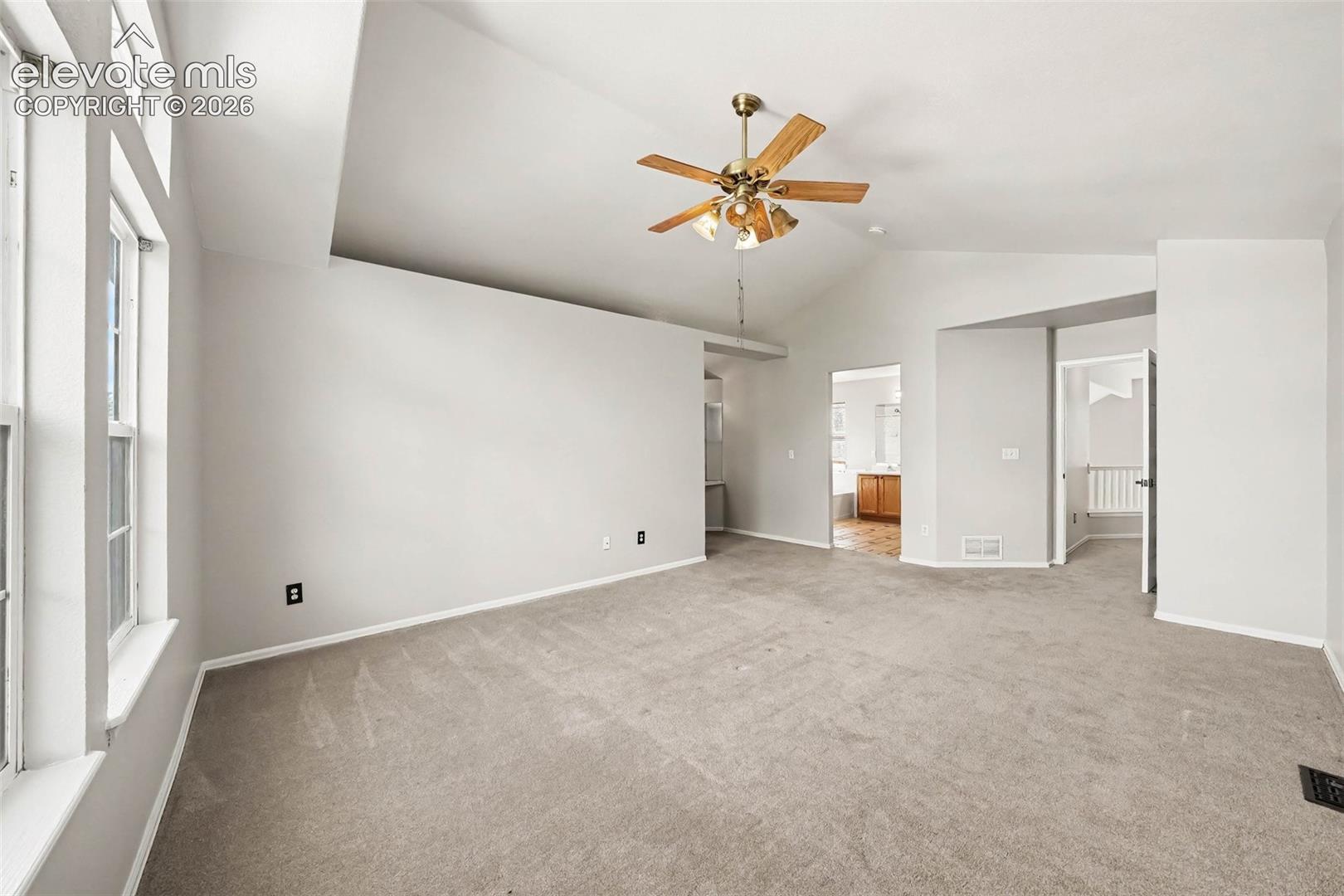Vaulted ceilings, a ceiling fan with integrated lighting, and light-toned wall finishes
