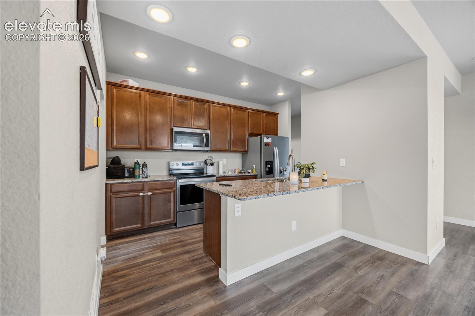 Stainless steel appliances include a range oven, microwave, dishwasher, and refrigerator.