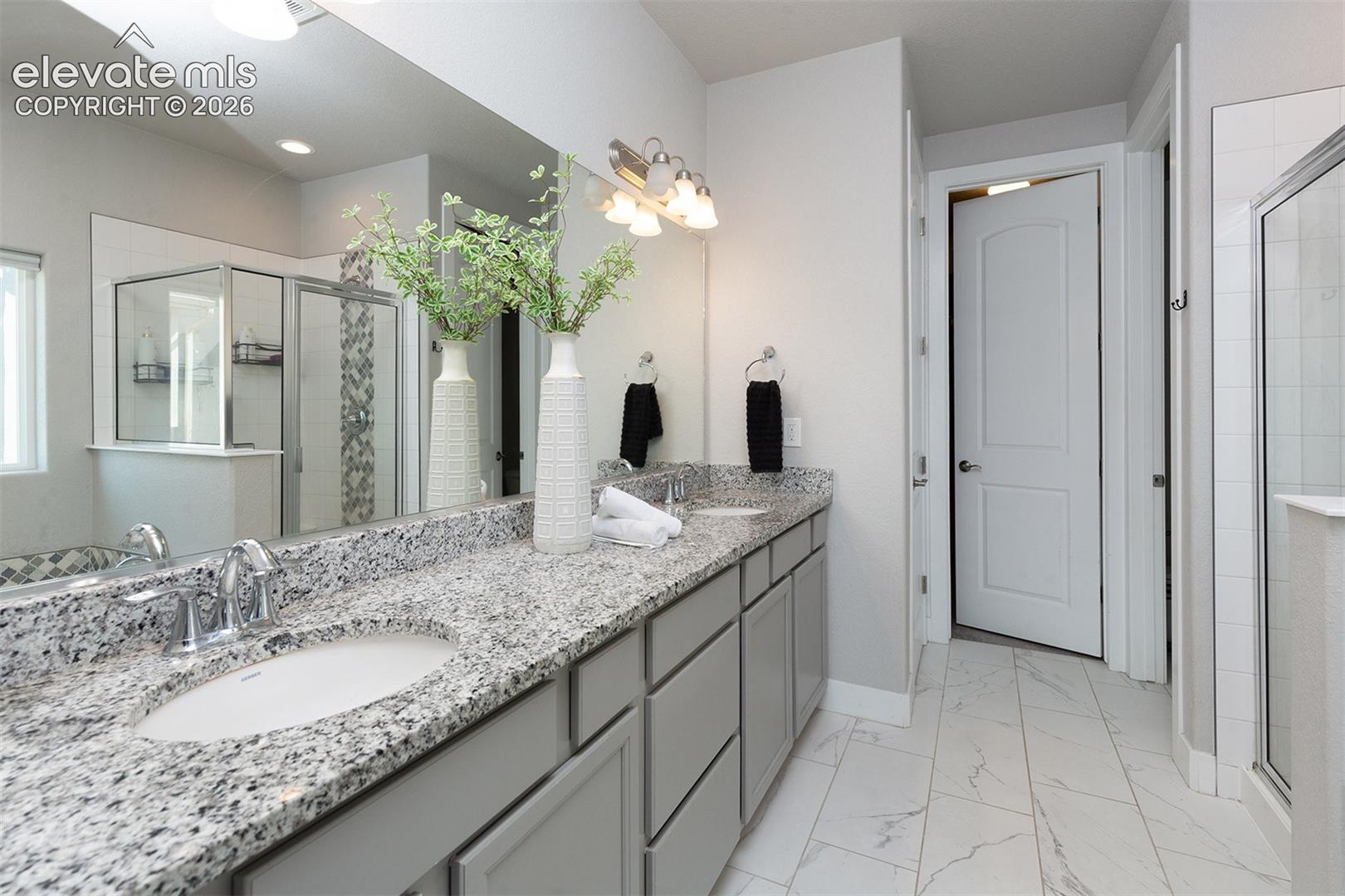 Dual vanity with granite countertops, light grey cabinetry, and chrome fixtures