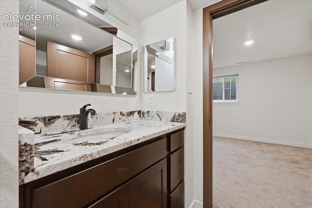 Vanity with a granite countertop, undermount sink, and dark wood-finish cabinetry