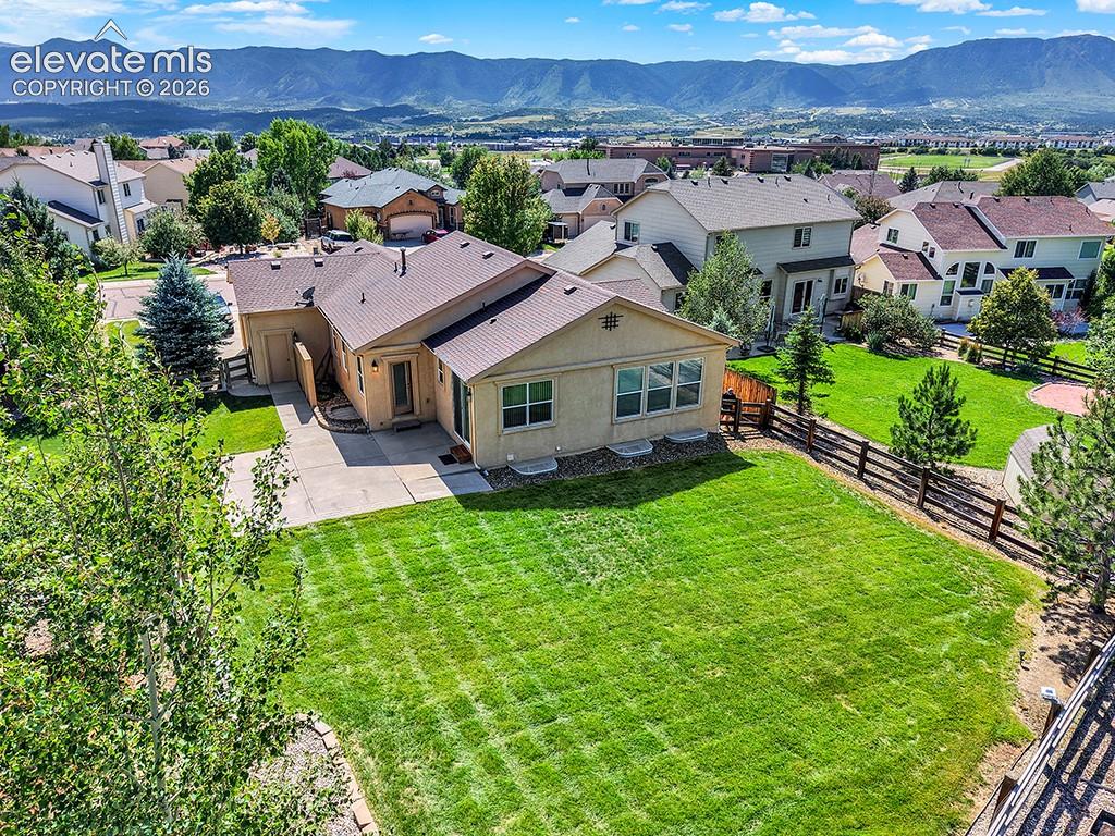 Expansive rear yard featuring a manicured lawn, established landscaping, and a partial wood fence