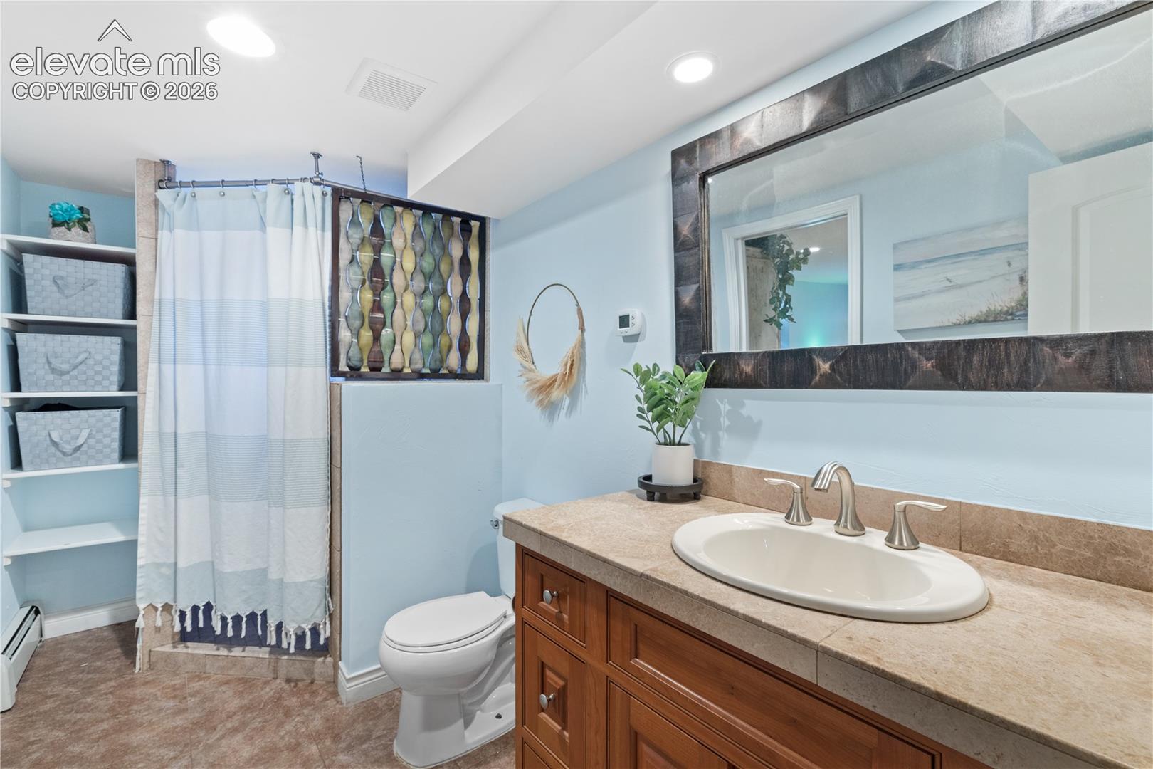 Bathroom featuring a wood vanity with an integrated sink, a tiled countertop, and a large framed mirror