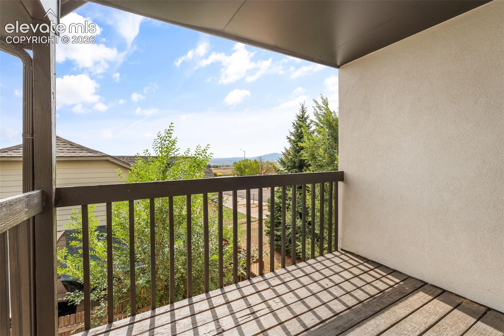 Covered balcony featuring wood-finish decking and a wooden balustrade