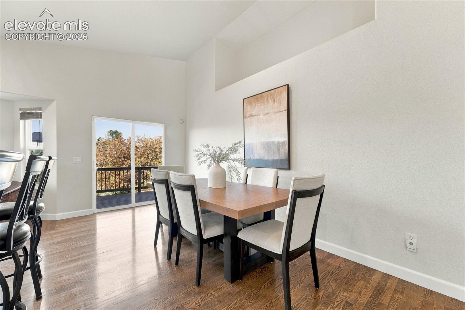 High-ceiling interior space featuring wood-finish flooring, recessed wall niche, and glass sliding door opening to an elevated exterior deck