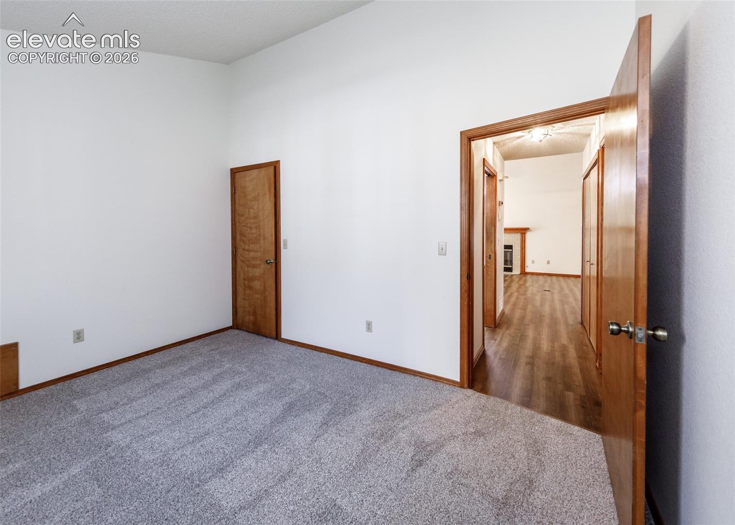 Carpeted room with vaulted ceilings and wood-finish doors