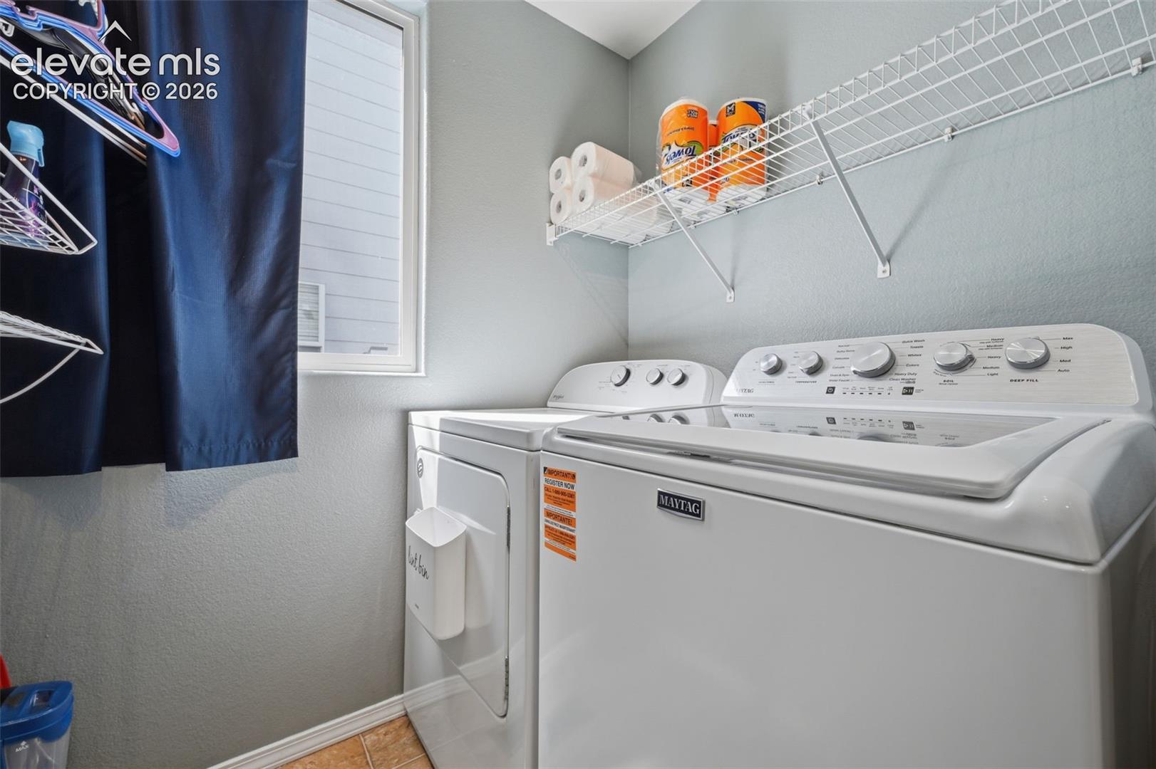 Laundry area featuring a window, white wire shelving, and light gray walls