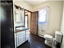 Bathroom featuring a white vanity cabinet with a stone-top integrated sink, wall-mounted medicine cabinet, and dark-toned flooring