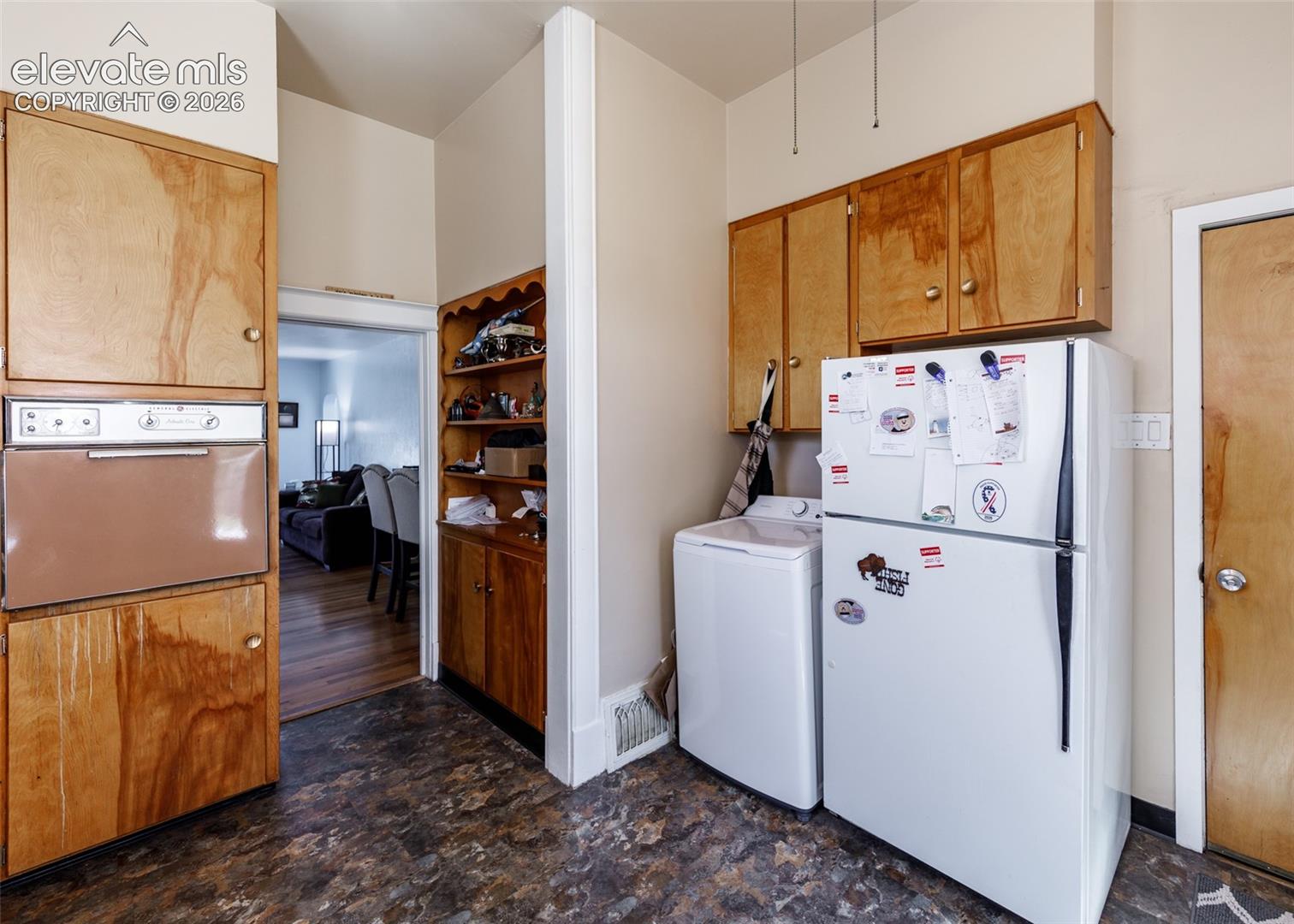 Built-in wall oven with wood cabinetry and complementary upper cabinetry