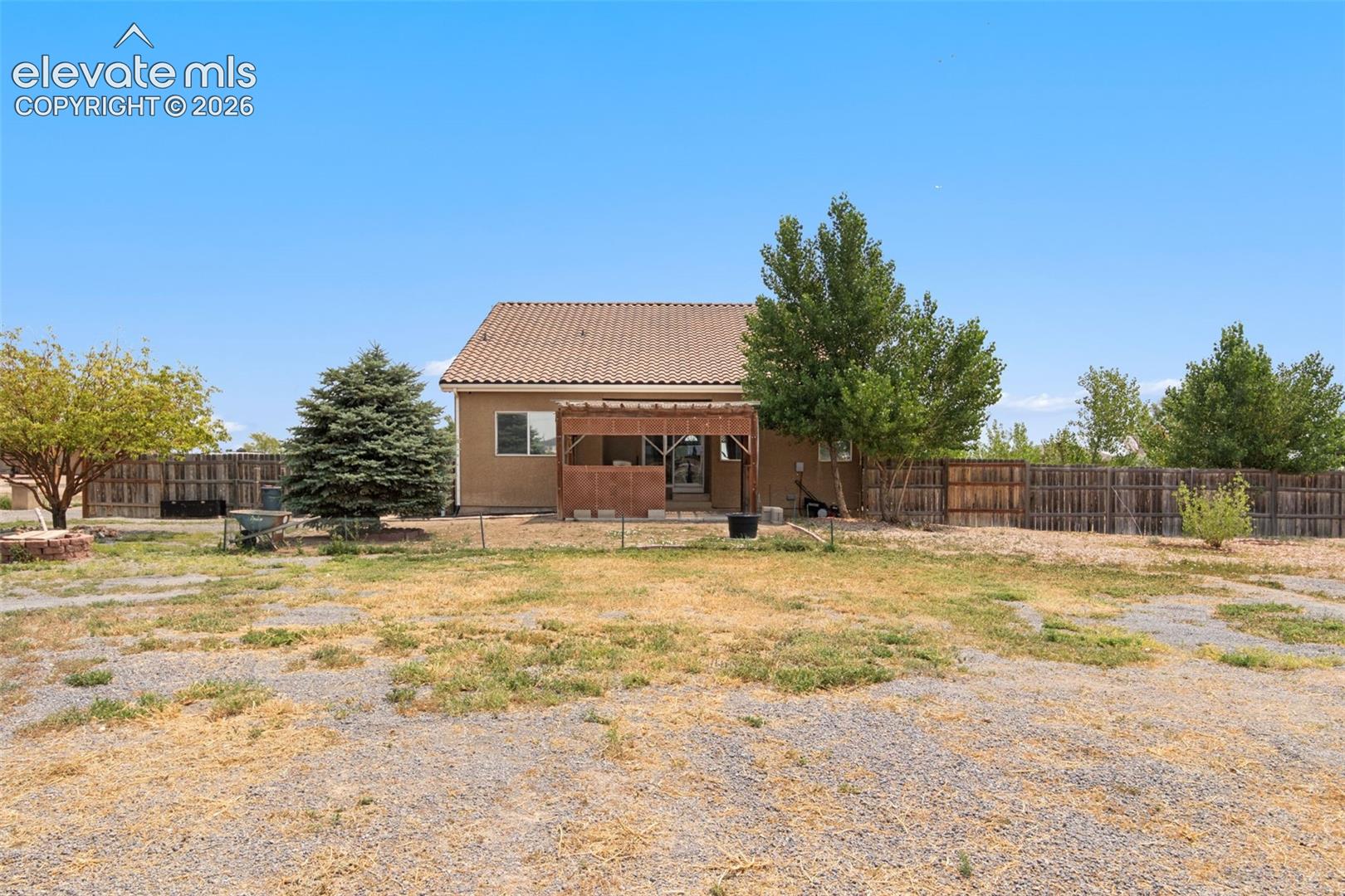 Rear exterior featuring a tile roof, wood pergola, and wood privacy fencing