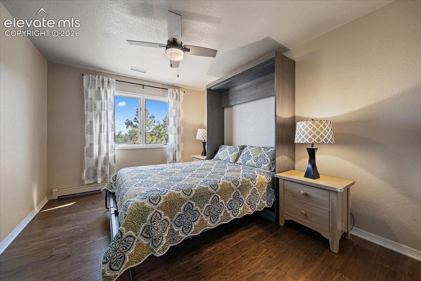 Built-in dark-toned cabinetry, wood-finish flooring, and a ceiling-mounted light fixture with integrated fan
