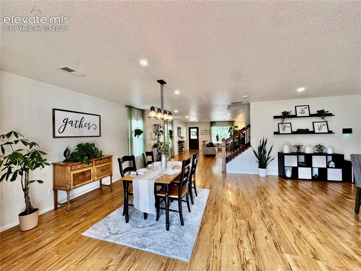 Open-concept dining area featuring wood-finish flooring, recessed lighting, and a linear chandelier