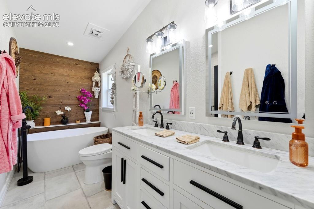 Dual vanity with white cabinetry, marble-finish countertop, and integrated sinks