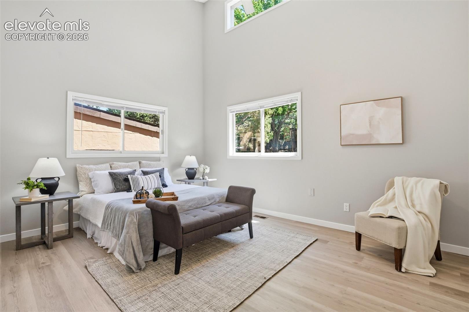 Bedroom featuring wood-finish flooring, high vaulted ceilings, and light gray wall paint