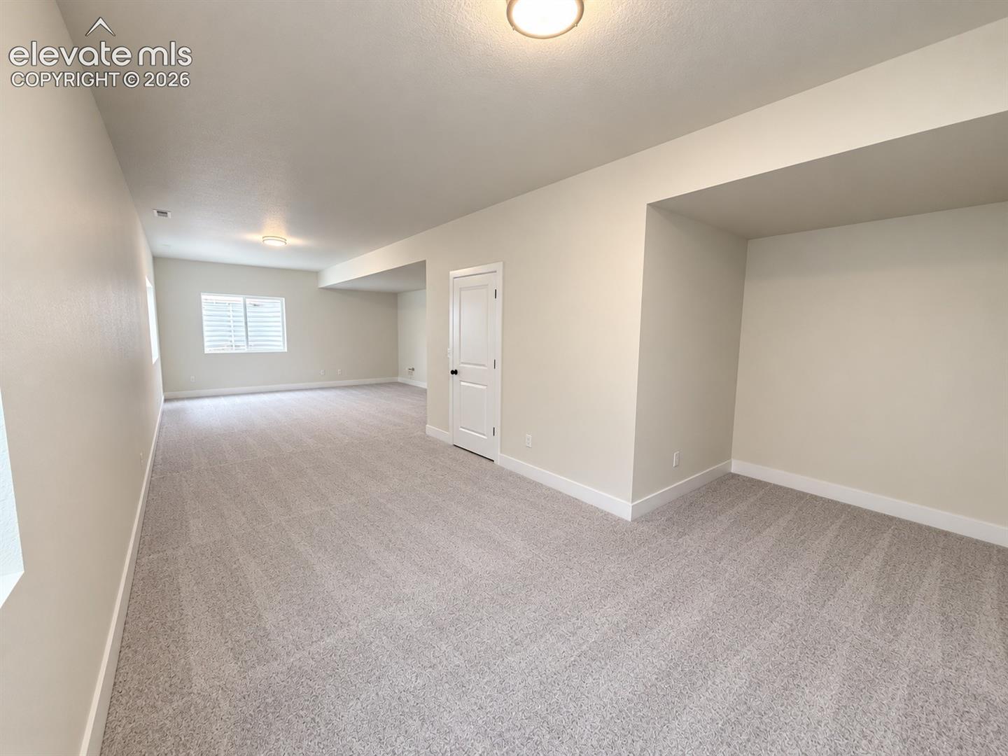 Neutral wall-to-wall carpeting, recessed ceiling lighting, single-panel interior door, and window with shutter-style blinds