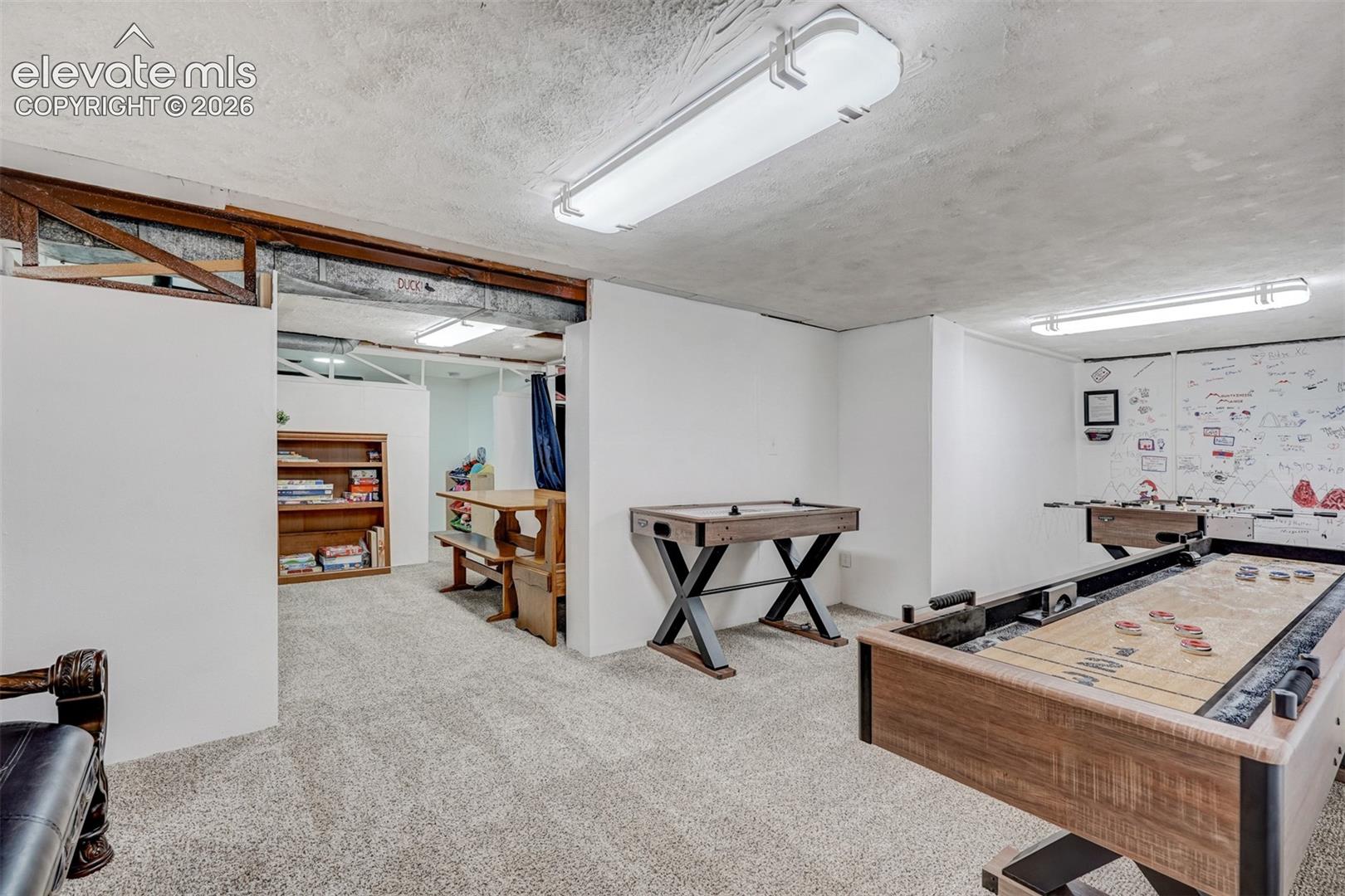 Carpeted recreation room with exposed ceiling beams and recessed lighting