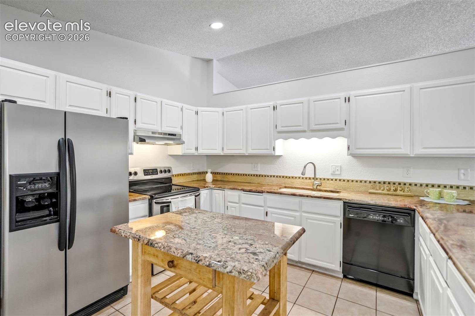Kitchen featuring white cabinetry, light-toned countertops, tile flooring, and stainless steel appliances