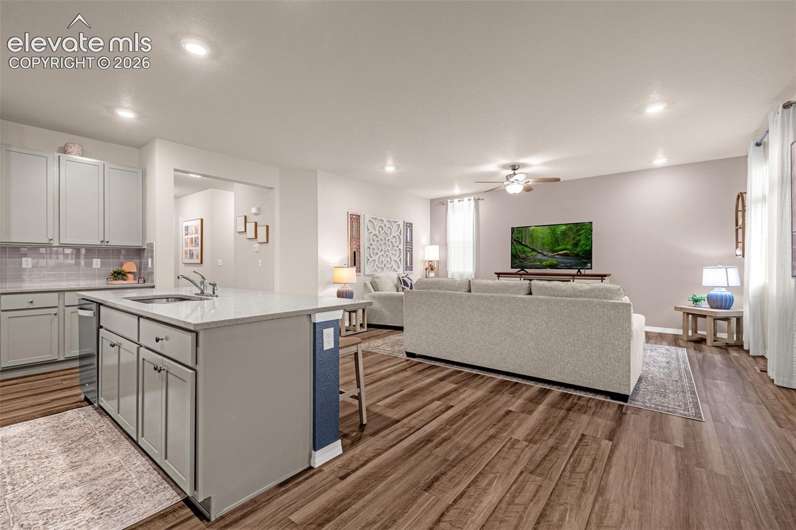 Open-concept living area featuring wood-finish flooring, recessed lighting, and a ceiling fan