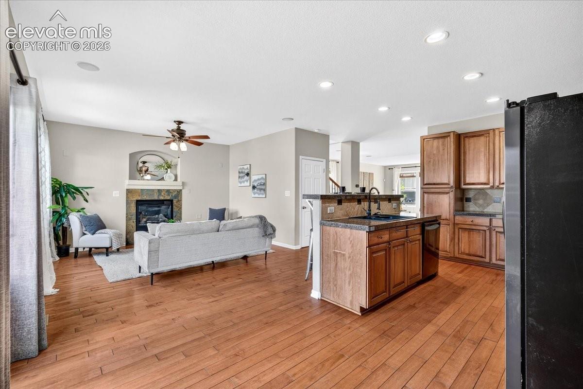 Hardwood-finish flooring, recessed lighting, and a kitchen featuring wood cabinetry and an island with a breakfast bar