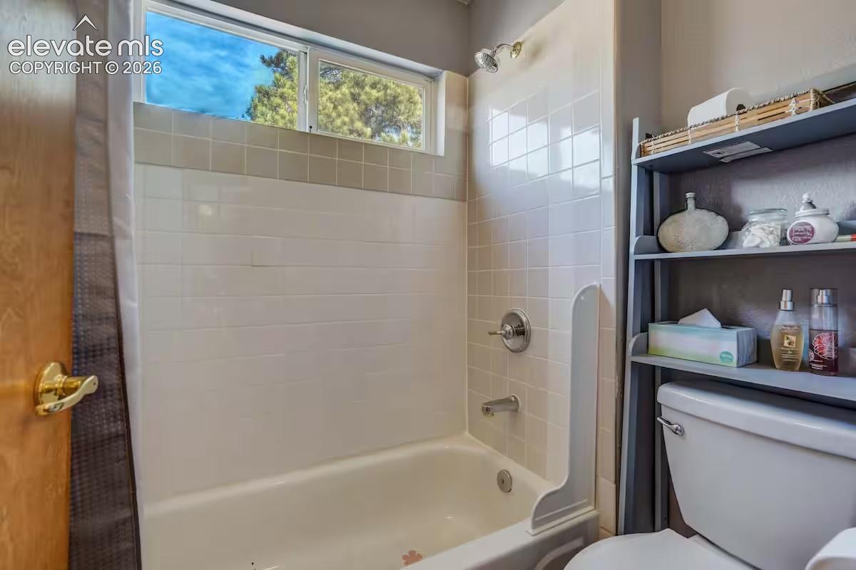Full bathtub with white tile surround and integrated shower head