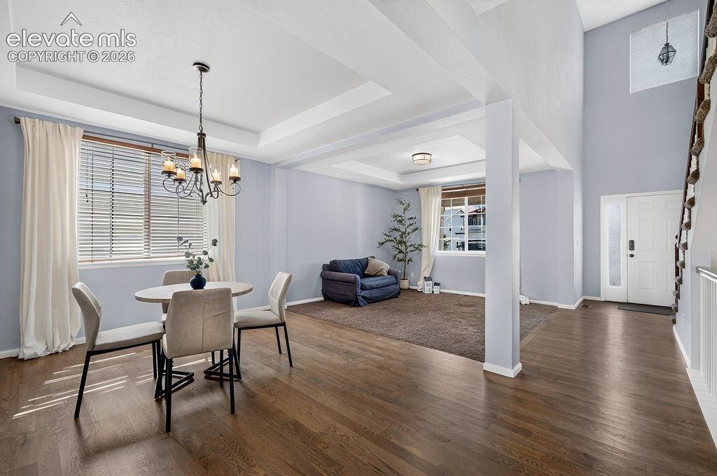 Hardwood-finish flooring throughout, tray ceiling with chandelier, and a two-story entryway with a frosted sidelight