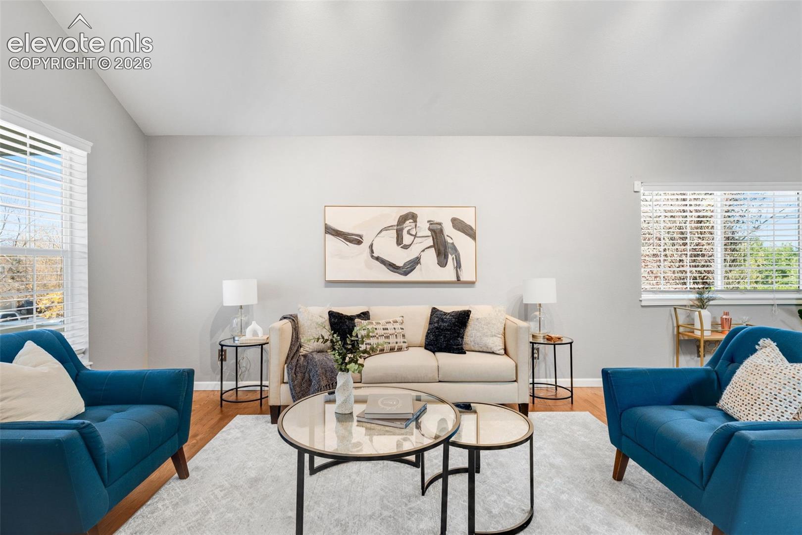 Vaulted ceiling, wood-finish flooring, and multi-pane windows with horizontal blinds