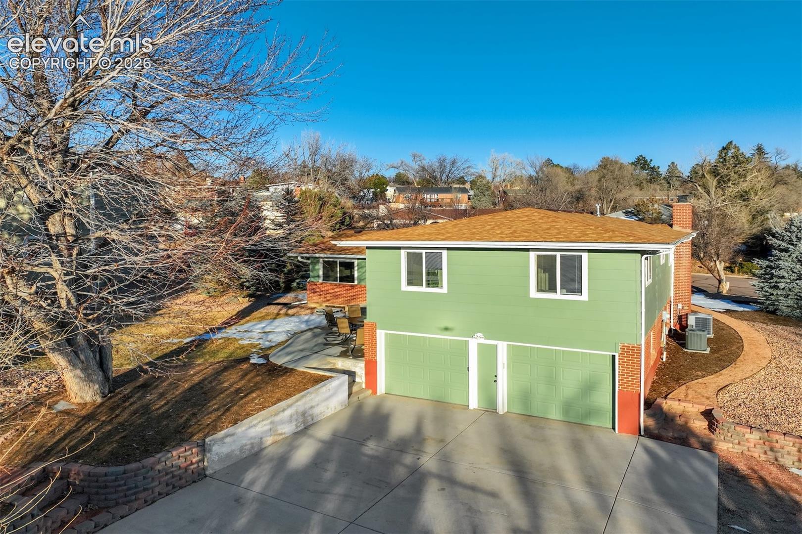 Two-story residence with a two-car garage, light green exterior siding, and a warm-toned roofing material