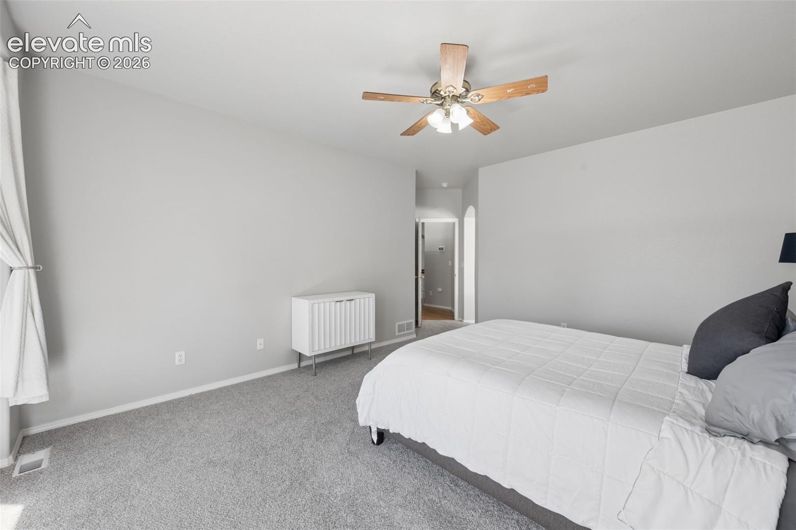 Neutral wall palette featuring an arched entryway and a five-blade ceiling fan with integrated light fixture