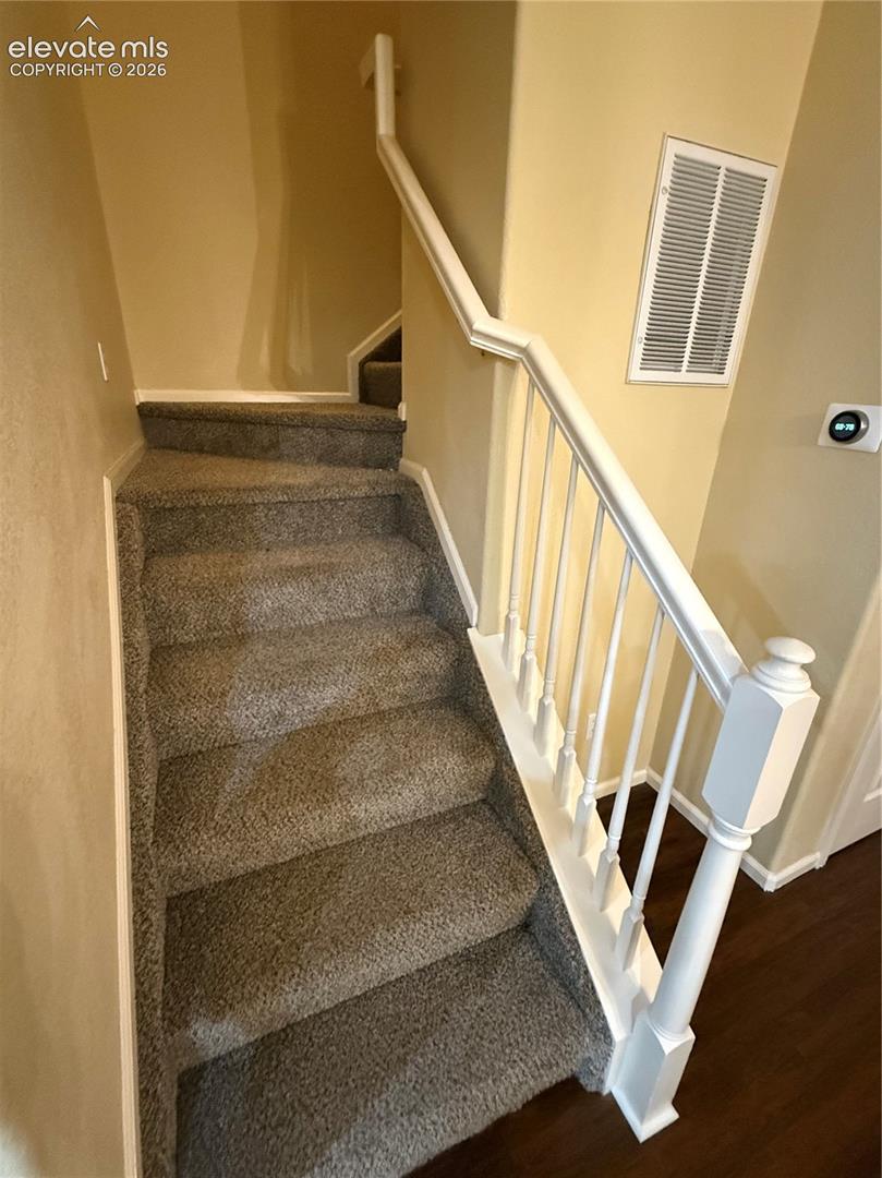Staircase featuring neutral carpet, white balusters, and handrail