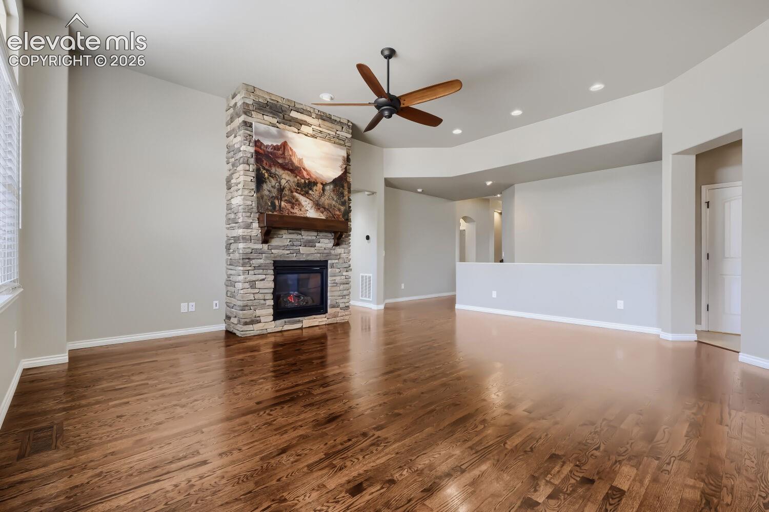 Living room with picture windows, stone fireplace, open concept design, gorgeous wood floors.
