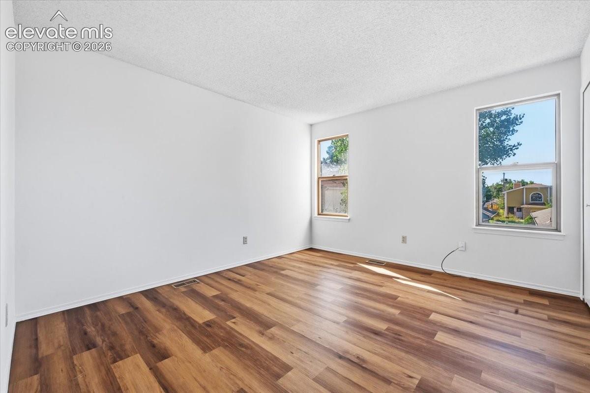 Sunlit upper-level bedroom with new LVP flooring at , Colorado Springs, CO.