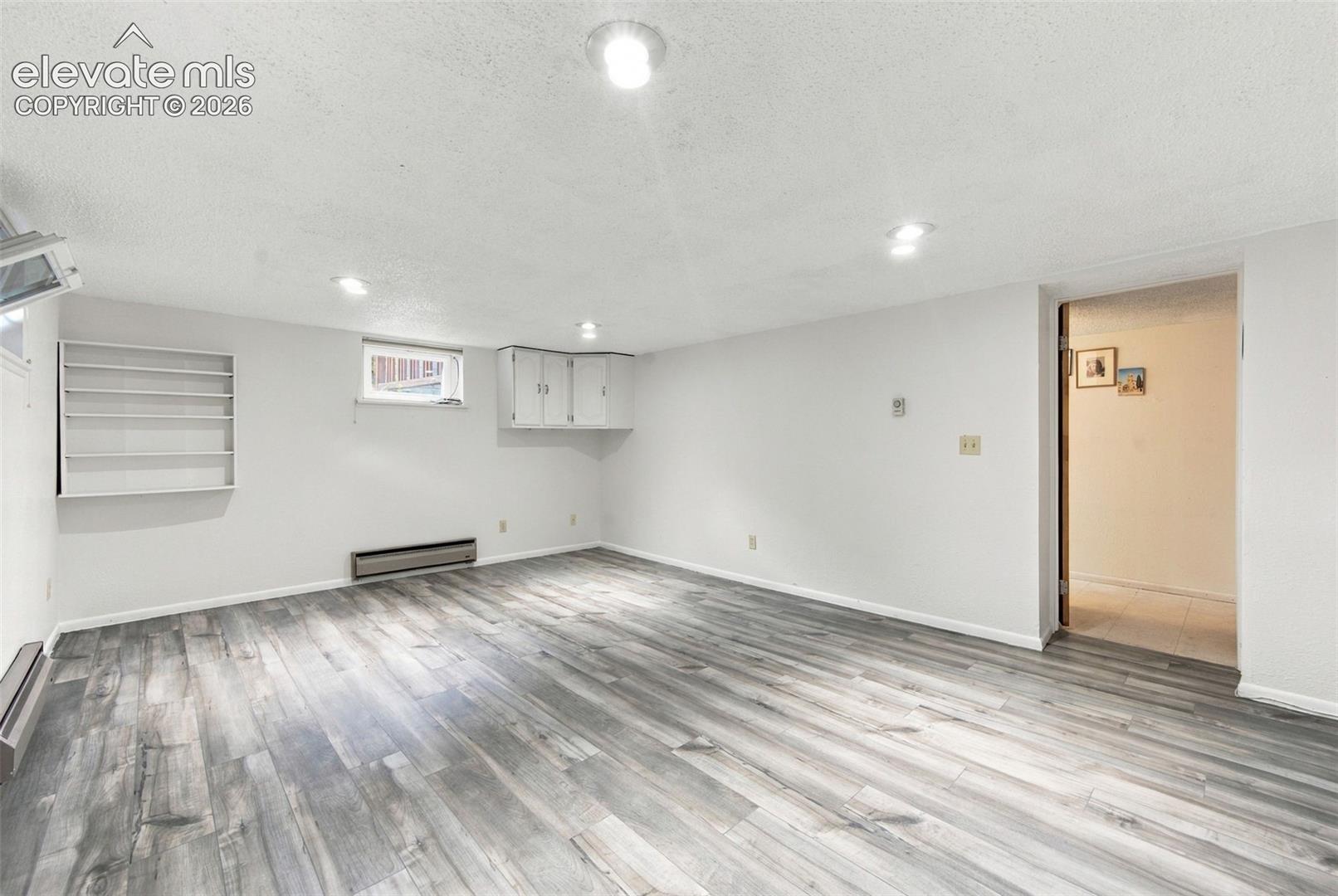 Wood-finish flooring, recessed ceiling lighting, built-in wall shelving, and overhead storage cabinetry