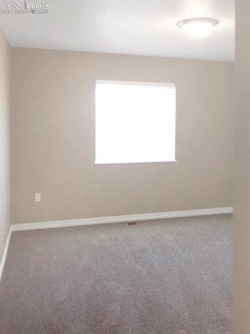 Empty room featuring light carpet and baseboards