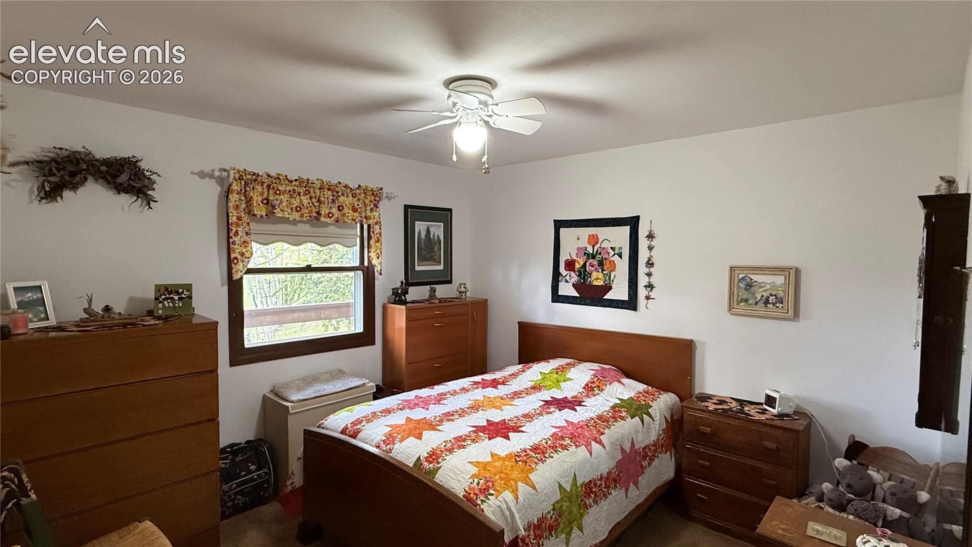 Interior room featuring white walls, a single window with a dark wood frame, and a white ceiling fan with integrated lighting
