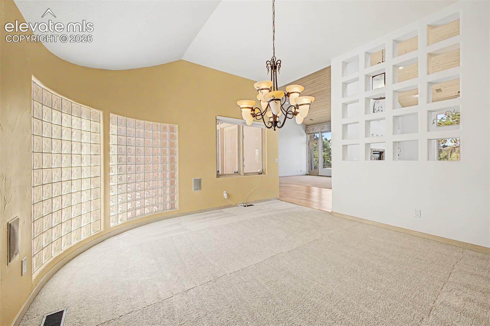 Vaulted ceiling with an ornate chandelier, curved wall with glass block windows, and a decorative partition wall